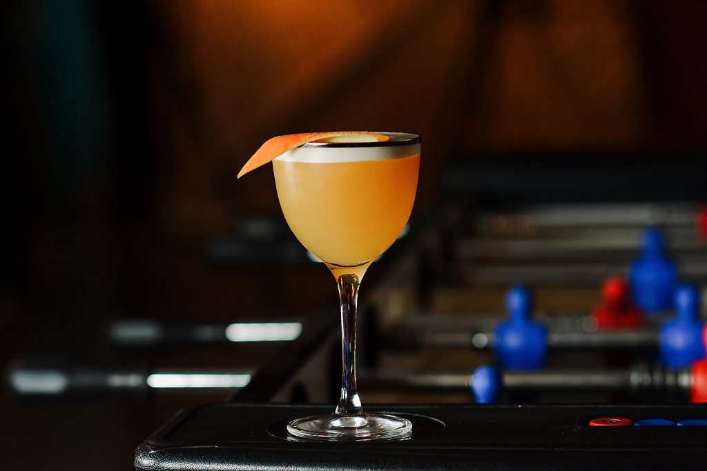A small orange cocktail made with a vegan alternative to egg white in cocktails