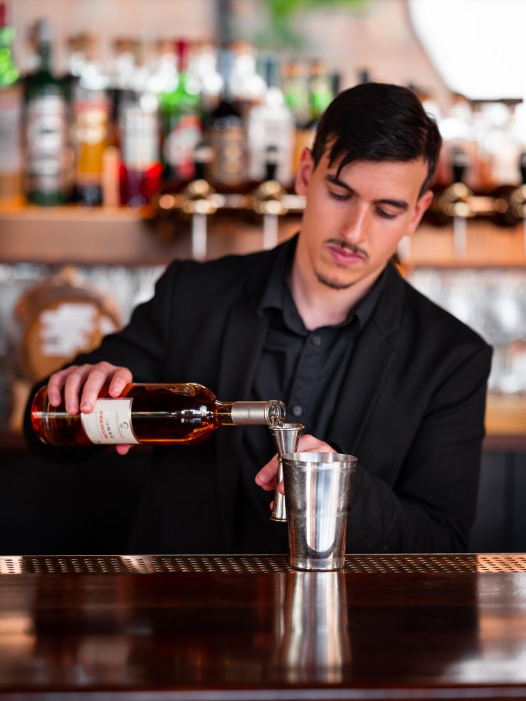 Photo of bartender pouring Cognac into a cocktail shaker.