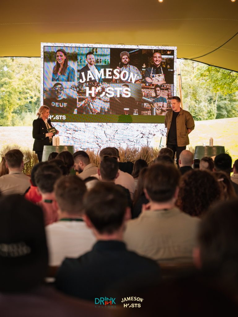 Photo of two a man and a woman on a stage giving a talk to people. You can read Jameson Hosts on a screen.