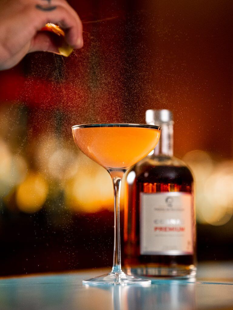 Photo of an orange Cognac Cocktail served in a coupe glass.